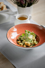 Sałatka w pięknym ozdobnym talerzu, podane na stole w restuaracji dodatkami są wypolerowane błyszczące srebrne sztućce, herbata oraz serwetki i laweda. Sałatka z ziołami i sosem białym.