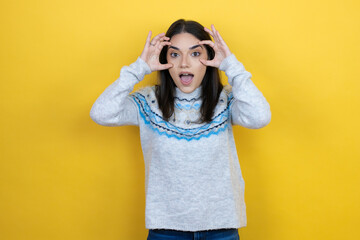 Young caucasian woman wearing casual sweater over yellow background Trying to open eyes with fingers, sleepy and tired for morning fatigue