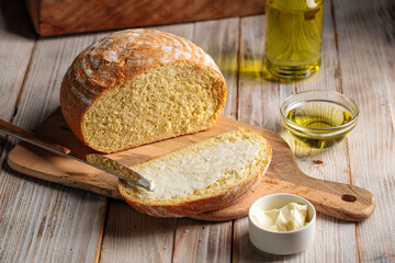 Top view on cut loaf of olive oil bread spread with butter on the wooden table