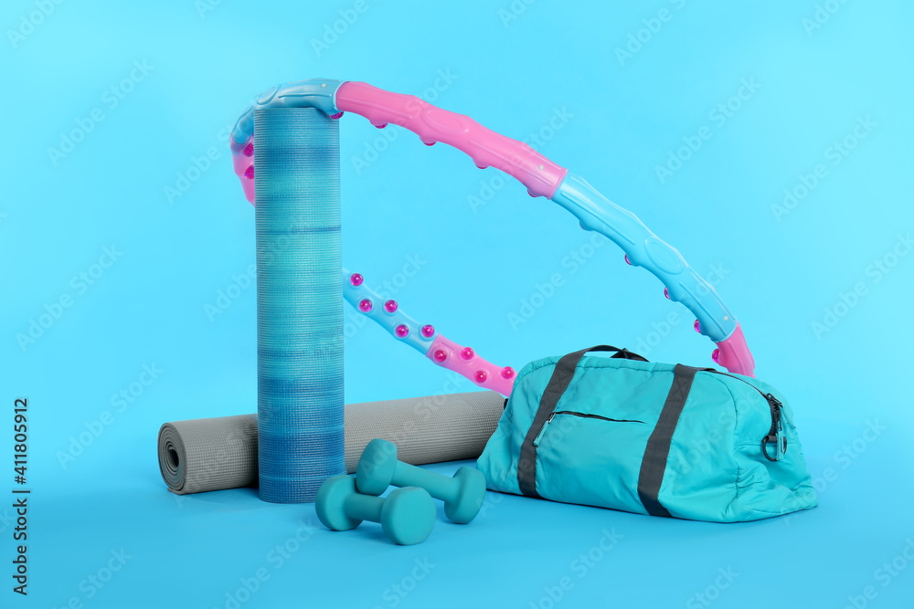 Poster Hula hoop, yoga mats, gym bag and dumbbells on light blue background