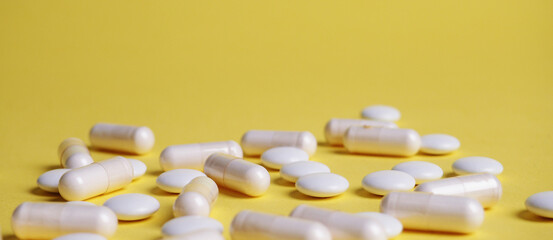 Banner a lot of different white tablets on a yellow background, the concept of health and medicine