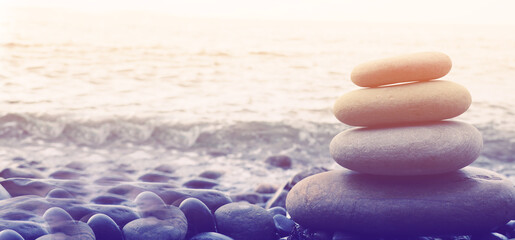 Balance, peace of mind, different sizes stones form a pyramid, Stones pyramid on pebble beach symbolizing stability, zen, harmony, balance. Shallow depth of field.