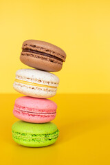 Various colorful macaroons on yellow background