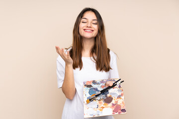 Young artist man holding a palette isolated on beige background unhappy and frustrated with something