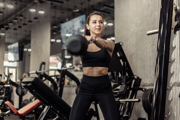 Naklejka na ściany i meble Young athletic woman working out with a kettlebell in her hands, doing swings in the gym