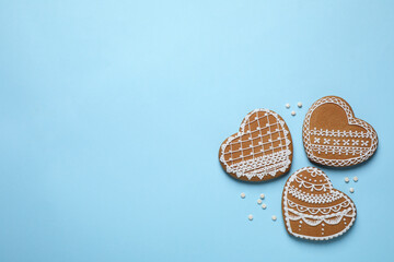 Tasty heart shaped gingerbread cookies on light blue background, flat lay. Space for text