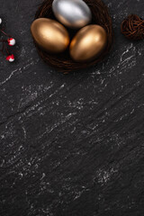 Golden and silver Easter eggs with flower on black background.