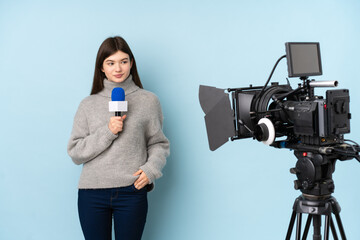 Reporter woman holding a microphone and reporting news over isolated blue background