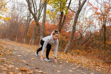 Young fit woman runner get ready run in autumn park or forest.
