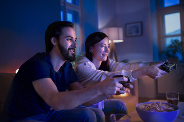 Young couple in love playing video games indoors at home.