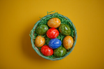 Easter card. Flat lay composition with easter eggs in a basket on yellow background.