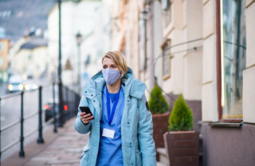 Fototapeta premium Woman healthcare worker outdoors on the way to work, coronavirus concept.