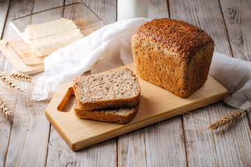 Side view on fresh baked cut whole wheat bread on the wooden board