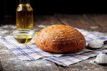 Obraz na płótnie Canvas Side view on loaf of rustic bread with olive oil on the wooden table