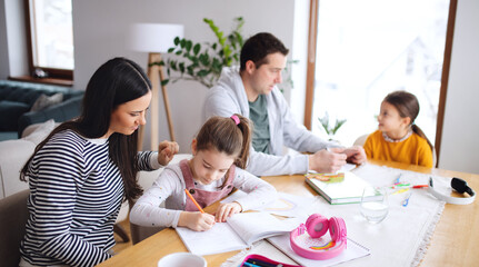 Parents with school girls indoors at home, distance learning.