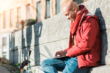 black man in the city of Lyon, France. On the street using his laptop