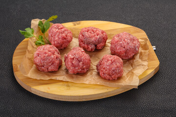 Raw meatball over wooden background