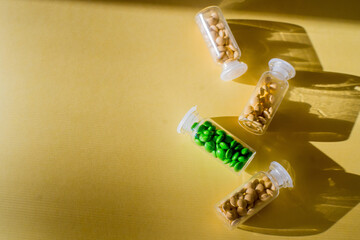 Multicolor tablets and pills capsules from glass bottle on yellow background Health care Close-up Horizontal banner Copy space