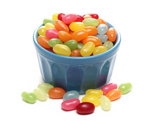 Jelly beans in blue porcelain bowl, colorful fruit candy dessert snack pile isolated on white background