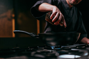 unrecognizable chef pouring oil into frying pan