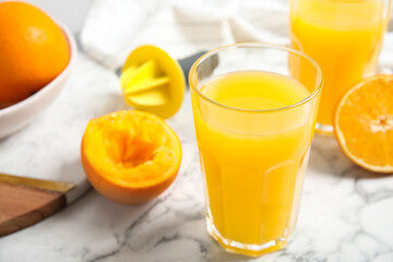 Fresh ripe orange, juice and reamer on white marble table, closeup. Space for text