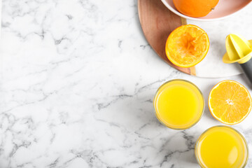 Fresh ripe orange, juice and reamer on white marble table, flat lay. Space for text