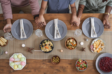 Top down view at African-American family praying at dinner table on Easter and holding hands, copy space