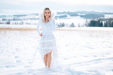 Fototapeta na wymiar Frau in weißem Schneekleid Haute Couture Hochzeitskleid Designerkleid weiß Winterlandschaft Schnee kalt Freude lacht