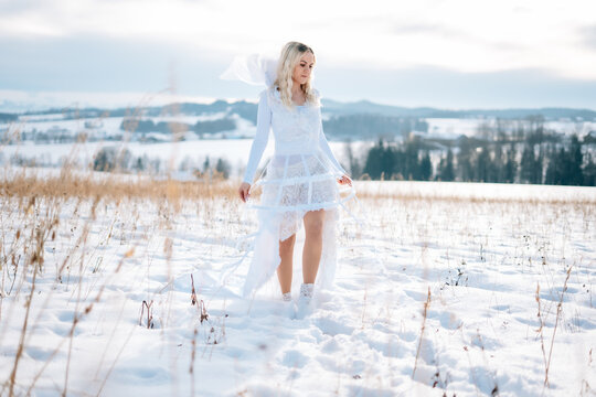 Frau in weißem Schneekleid Haute Couture Hochzeitskleid Designerkleid weiß Winterlandschaft Schnee kalt Freude lacht