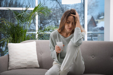 Woman holding glass of medicine for hangover at home