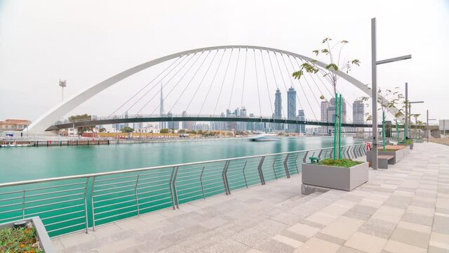 Pedestrian Bridge over the Dubai Water Canal cloudy day timelapse which links Dubai Creek to Jumeirah Beach weaving through Deira, Downtown Dubai and Safa Park. Skyscrapers skyline. Dubai, United Arab