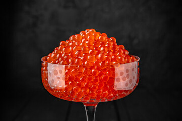 Red caviar in a crystal bowl on a black background. Delicacy product of the highest quality.