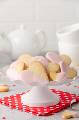 Obraz na płótnie Canvas Heart-shaped cookies with pink chocolate glaze for Valentine's Day on a white stand on the gray background. Valentine's Day food background.