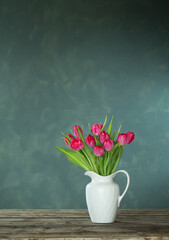 beautiful tulips in white jug on dark background