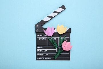 Clapperboard and origami tulips on a blue background. Filmmaking concept. Top view