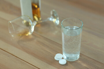 Glass of water and pills on table indoors, space for text. Hangover remedy