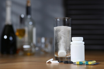 Glass of hangover remedy and pills on table indoors. Space for text