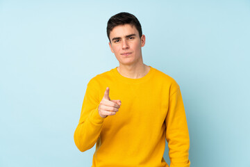 Teenager caucasian handsome man isolated on purple background frustrated and pointing to the front