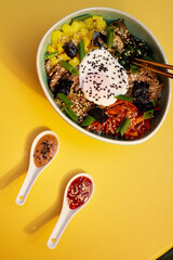 Top view of Bibimbap, a classic Korean meal. Rice is topped with seasoned vegetables, meat and a sunny side up fried egg on top. Spicy chili sauce can be added to finish off this savoury Asian dish.