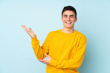 Teenager caucasian handsome man isolated on purple background extending hands to the side for inviting to come