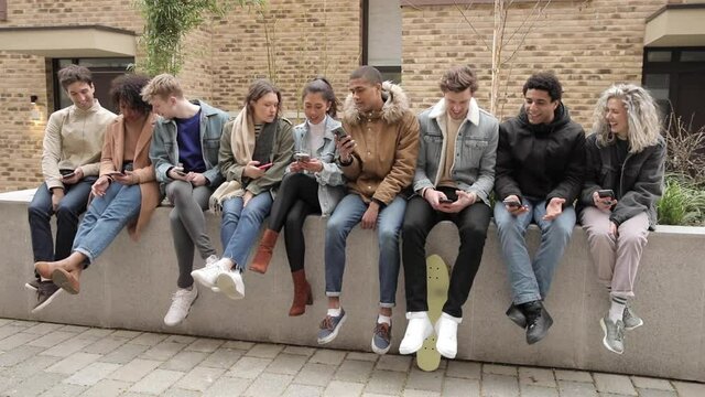 Multiethnical group of people with smartphones in the city - Big group of people sitting together and looking at their phones - Social media concept and addiction, millennials lifestyle in London