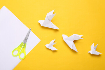 Origami hand made paper doves on yellow background