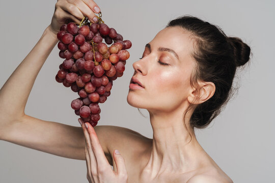 Beautiful half-naked woman posing with bunch of grapes