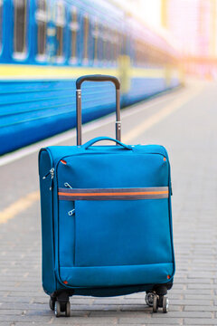 Hand luggage on the platform near the train carriage. Blue suitcase for travel and leisure