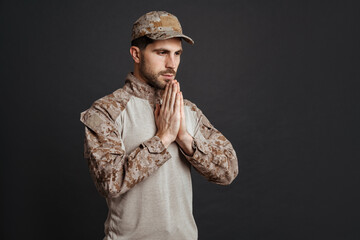 Focused masculine military man making praying gesture