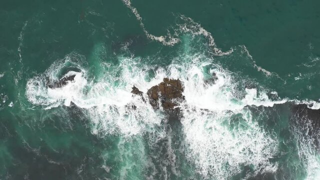Aerial top view of rocks in the sea - Aerial video of majestic waves splashing on the rocks in Scotland - Travel and nature concepts