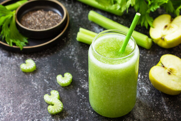 Healthy diet and nutrition, vegan, alkaline, vegetarian concept. Green smoothie with celery and apple on a dark stone countertop.