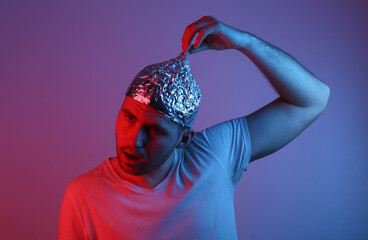 Crazy Bearded Man in aluminum foil cap in red blue neon light. Conspiracy
