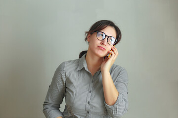 Smiling pretty brunette girl with eyeglasses calling phone and talking isolated over gray background
