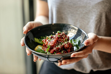 Girl holding a bowl of marinated chicken in spicy sauce with daikon 